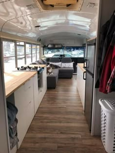 the interior of an rv with wood flooring and white walls, windows, and cabinets