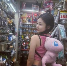 a woman is holding a pink teddy bear in a toy store with other items on the shelves