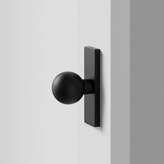 a black door handle on the side of a white wall next to a light bulb