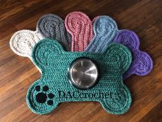 a crocheted dog bone with paw prints and a metal bowl cover on the floor