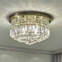 a crystal chandelier hanging from the ceiling in a room with white walls and curtains