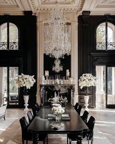 an elegant dining room with chandelier and black chairs in front of the fireplace