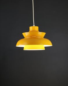 a yellow light hanging from a ceiling in a dark room with no one around it