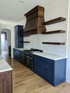 a kitchen with blue cabinets and an oven in the center is painted white, while wood shelves are on either side of the stove