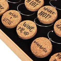 six wine corks with words written on them in a wooden box and hanging from hooks