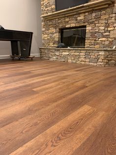 an empty living room with wood floors and stone fireplace