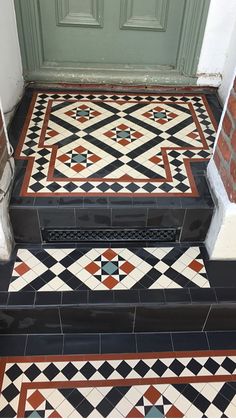 an entryway with black and white tiled flooring next to a green front door