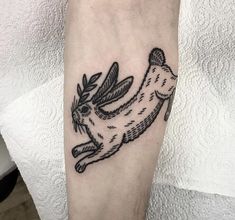 a black and white tattoo of a dog with leaves on it's back leg