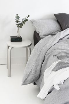 a bed sitting next to a white table with a plant on it