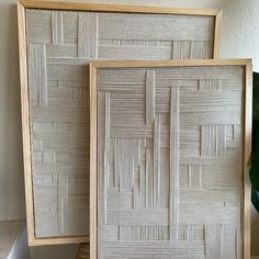 two wooden frames sitting next to each other on top of a table in front of a potted plant