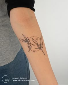 a small tattoo on the arm of a woman with two birds flying over her head