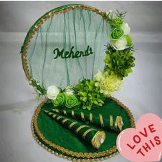 a green hat with flowers and greenery on it is sitting in front of a sign that says mehns