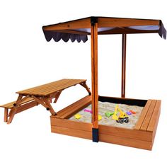 a wooden sandbox with an umbrella and picnic table in the middle, on a white background