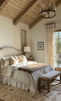 a large bed sitting in a bedroom under a chandelier next to a window