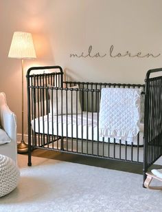 a baby's crib in the corner of a room with a name written on the wall