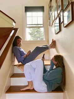 two women are sitting on the stairs and one is holding a cell phone in her hand