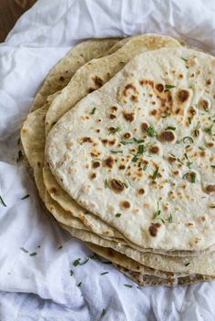 three tortillas are stacked on top of each other, with herbs sprinkled on them