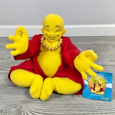 a yellow stuffed toy sitting on top of a wooden floor next to a blue book