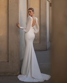 a woman in a white dress is leaning against a wall with her back to the camera