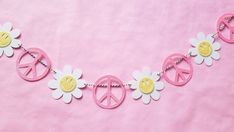 a pink and white peace sign with flowers on a string hanging from it's side