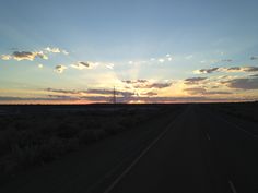 the sun is setting over an empty road in the middle of nowhere, with no cars or people on it