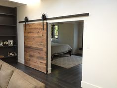 a living room with a couch and sliding barn door in the middle, leading to a bedroom