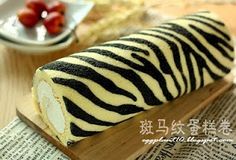 a zebra print roll sitting on top of a wooden cutting board next to strawberries