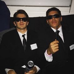 two men sitting next to each other wearing sunglasses