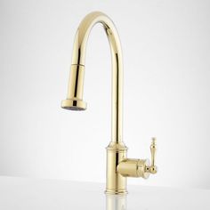 a kitchen faucet with gold colored fixtures on a white countertop in front of a plain background