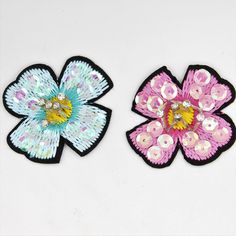 two flower shaped brooches sitting next to each other