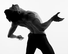 a shirtless man reaching for a frisbee in the air with his right hand