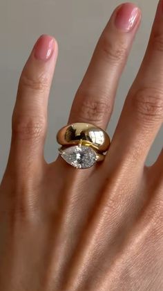 a woman's hand with two gold rings on it and a diamond in the middle