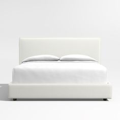 a bed with white sheets and pillows on it