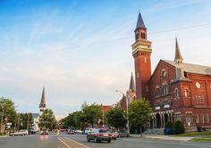 an old red brick church with a steeple and clock tower in the background on a city street