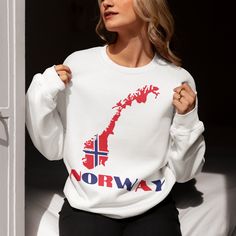 a woman wearing a white sweatshirt with norway printed on the front and back in red, white, and blue