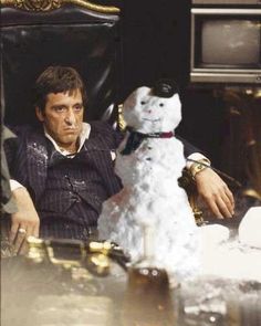 a man sitting in a chair next to a snowman