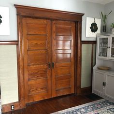 a room with two wooden doors and a rug on the floor in front of it