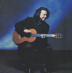 a man sitting on a chair holding a guitar