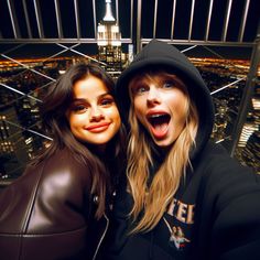 two young women standing next to each other in front of a cityscape at night