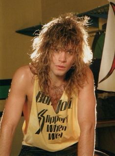 a man with long hair sitting in front of a surfboard