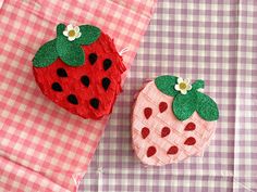 two strawberries sitting on top of a pink and white checkered table cloth next to each other