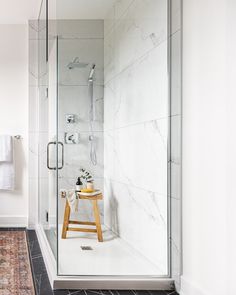 a walk in shower sitting next to a white sink and toilet on top of a wooden stool