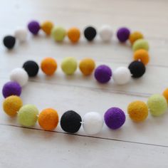 a multicolored necklace on a wooden table with white, black, and yellow beads