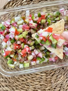 a person is holding a tortilla in a glass dish with chopped veggies