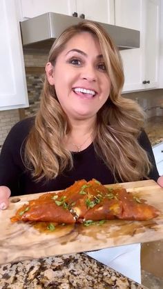 a woman holding up a pizza on a cutting board