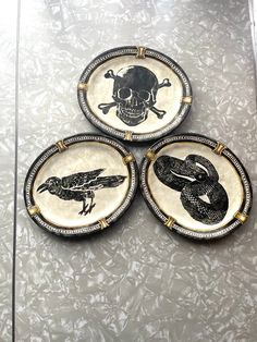 three decorative plates with black and white designs on them, each decorated with a snake