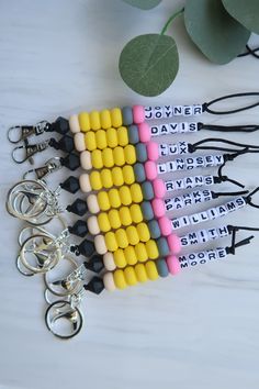 four key chains with different colored beads on them and some leaves in the back ground