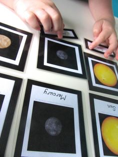 a child's hands on some cards with pictures of planets