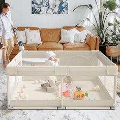 a woman standing next to a couch in a living room with a baby crib