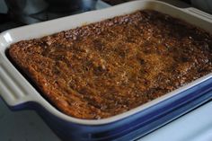 a blue and white casserole dish filled with food on top of a stove